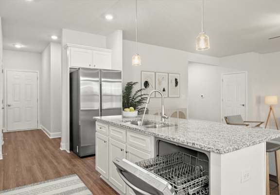 A modern kitchen with a white color scheme and a marble countertop.
