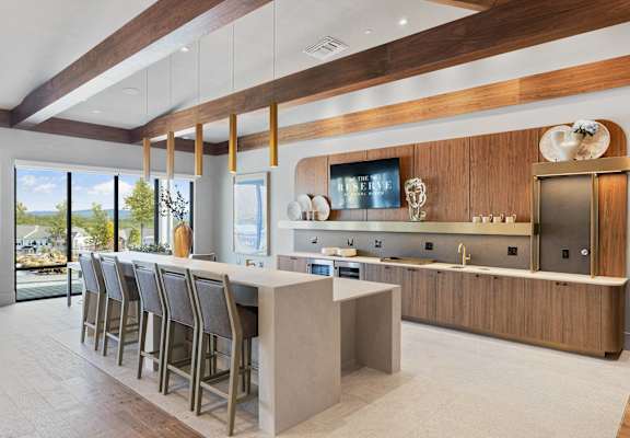 A modern kitchen with a bar area and a television mounted on the wall. at The Reserve at Pearl River Apartments, New York