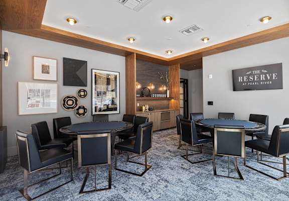 A room with a black table surrounded by black chairs. at The Reserve at Pearl River Apartments, New York