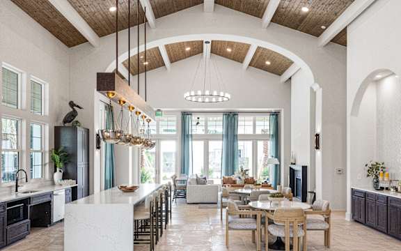 A large open kitchen and dining room with a white island and wooden beams.