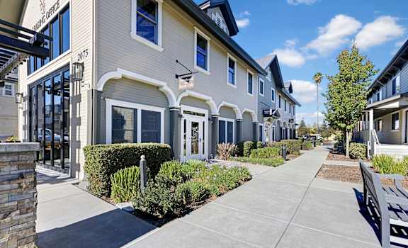 A row of houses with a sidewalk in front.