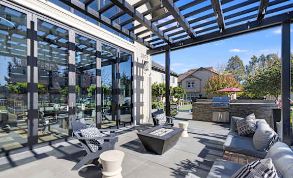 A modern outdoor patio with a glass wall and a stone fireplace.