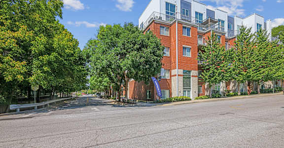 A street view of a residential area with apartment buildings and trees.