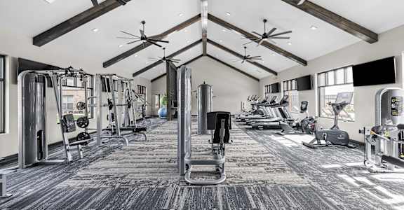 A spacious gym with a variety of equipment and a dark floor.