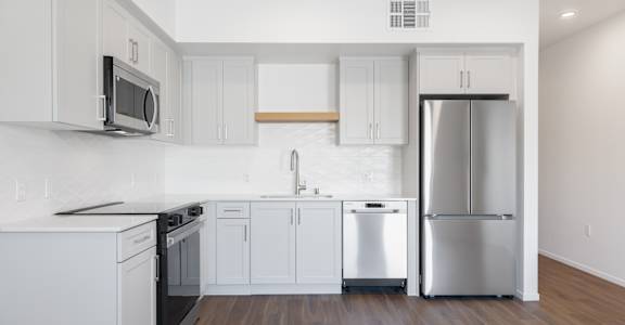 A kitchen with white cabinets and a stainless steel refrigerator.