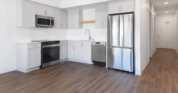 A modern kitchen with stainless steel appliances and wooden floors.