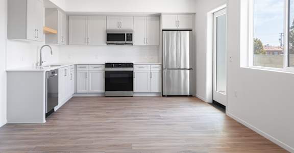 A modern kitchen with stainless steel appliances and wooden floors.