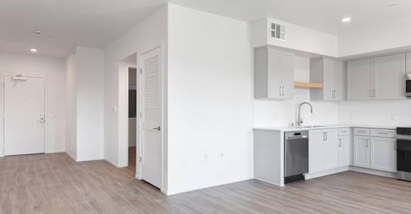 A kitchen with white cabinets and a wooden floor.