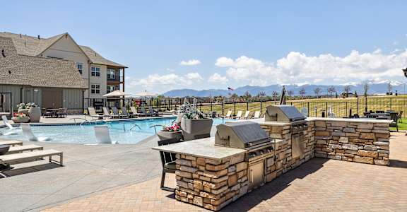 A large outdoor swimming pool with a stone wall and loungers.