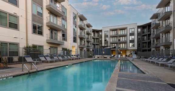 A large swimming pool in front of apartment buildings.