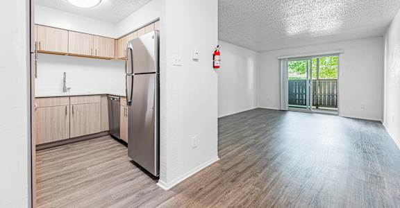 A kitchen with a refrigerator and wooden floors.