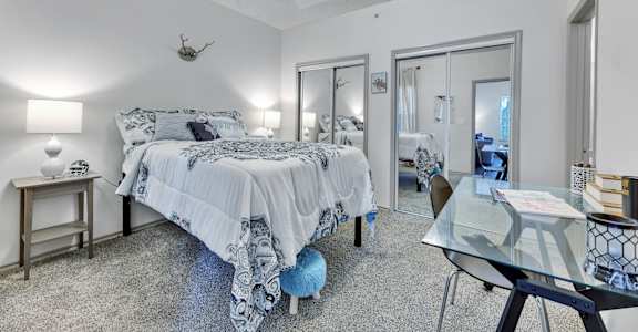 a bedroom with a bed and a glass desk