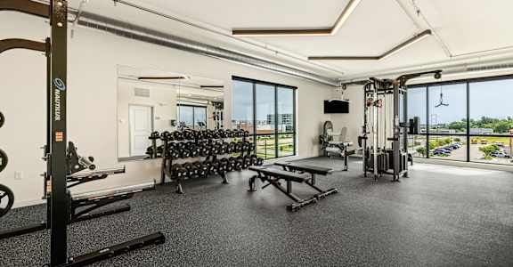 a gym with weights machines and windows and a view of the city at The Standard on 32nd, West Fargo, North Dakota