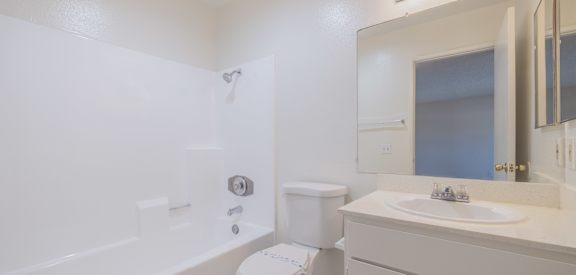 A white bathroom with a toilet, sink, and mirror.