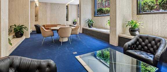 A conference room with a glass table and leather chairs.