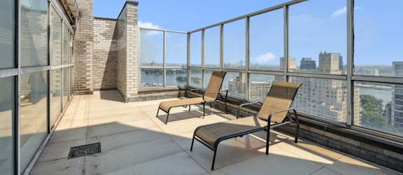 A balcony with chairs and a table overlooking a cityscape.
