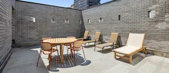 A patio with a table and chairs is surrounded by brick walls.