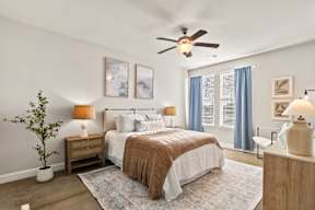 A bedroom with a bed, nightstands, and a ceiling fan.