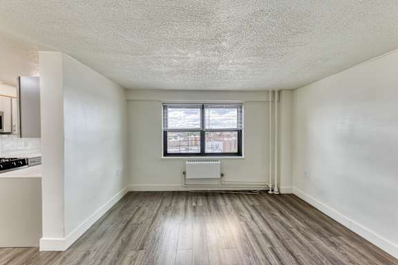 A spacious room with a window and a radiator on the floor.