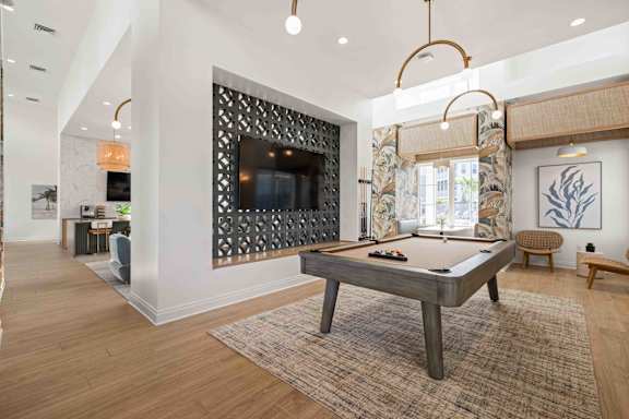 A pool table is in the middle of a room with a television and a chair.at Verity Luxury Apartments, Vero Beach, FL 32960