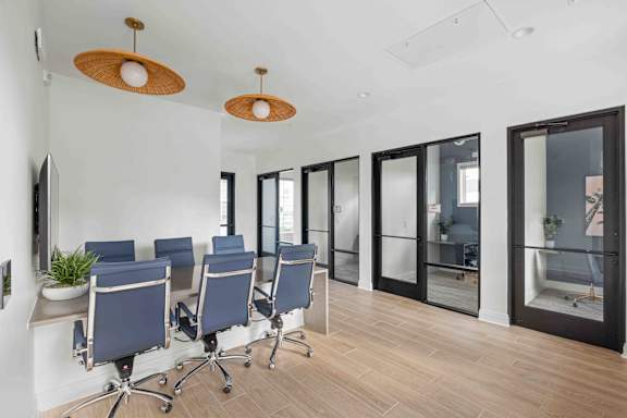 A conference room with blue chairs and wooden floors.at Verity Luxury Apartments, Vero Beach, FL 32960