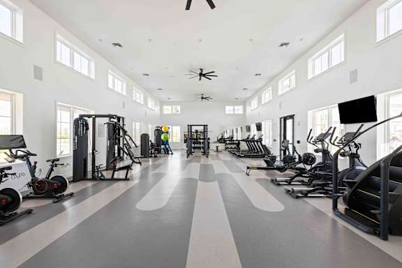 A spacious gym with a variety of exercise equipment and a person working out.at Verity Luxury Apartments, Vero Beach, FL 32960
