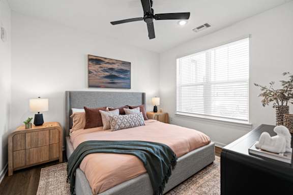 A bedroom with a bed, a ceiling fan, and a painting on the wall.at Verity Luxury Apartments, Vero Beach, FL 32960
