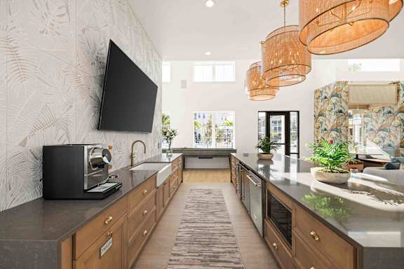 A modern kitchen with a black television mounted on the wall.at Verity Luxury Apartments, Vero Beach, FL 32960