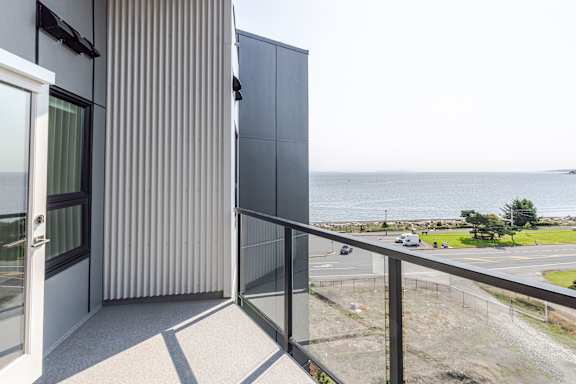 A balcony with a view of the ocean and a parking lot.