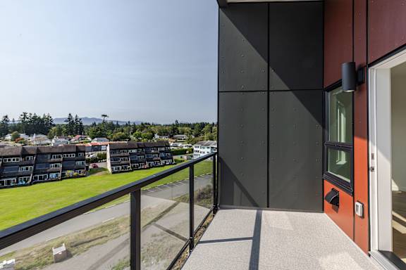 A modern building with a balcony overlooking a residential area.