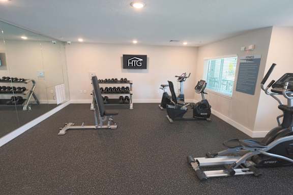 A gym with a variety of equipment including treadmills, stationary bikes, and weight racks.