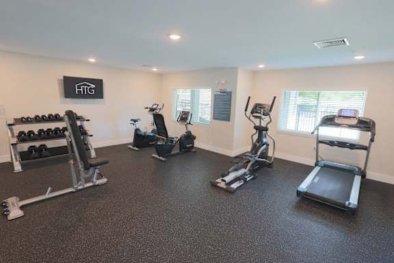A gym with a variety of equipment including a treadmill, weights, and exercise machines.