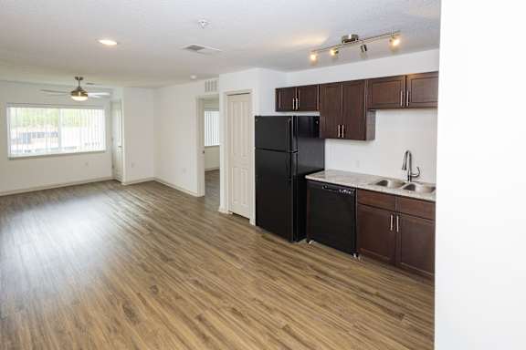 A kitchen with a black refrigerator and wooden floors.