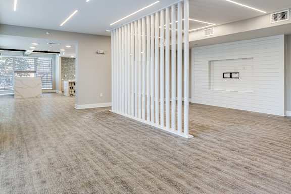 A room with a white column and wood flooring.