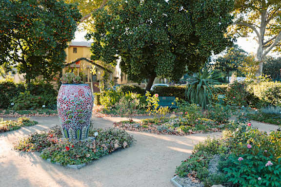 A garden with a large vase in the middle of a circular flower bed.