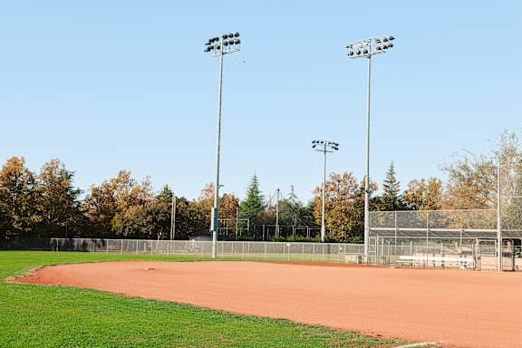 A tennis court with two lights on poles on either side.