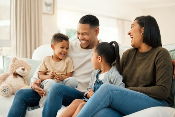 a family sitting on a couch with a teddy bear
