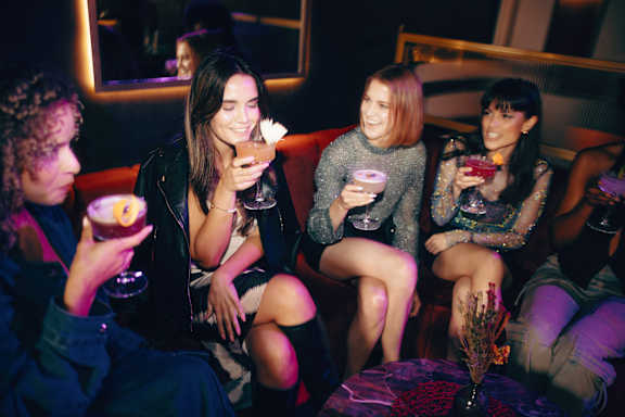A group of friends are sitting on a couch and enjoying drinks together.