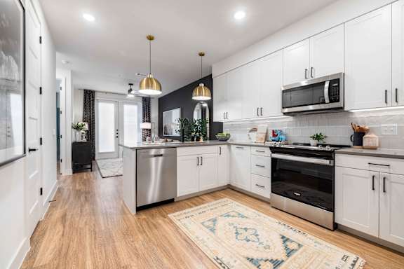 A modern kitchen with white cabinets and a wooden floor.