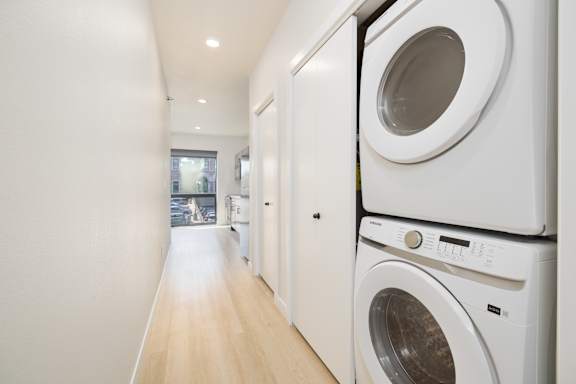 A row of white front loading washing machines in a laundry room.