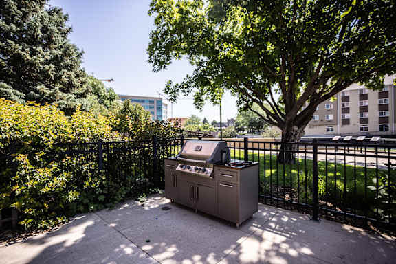 A grill is on a table outside behind a fence.