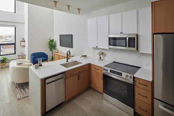 A modern kitchen with a white countertop and stainless steel appliances.