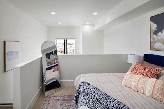 A bedroom with a bed, pillows, and a window.