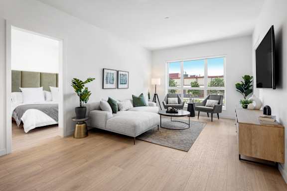 A modern living room with a grey sofa, a coffee table, and a large window.