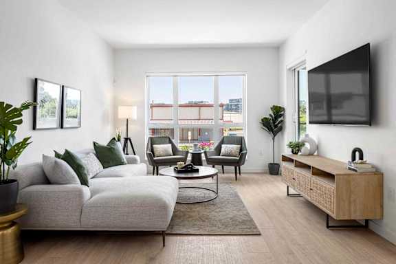 A living room with a white couch, a coffee table, and a large window.