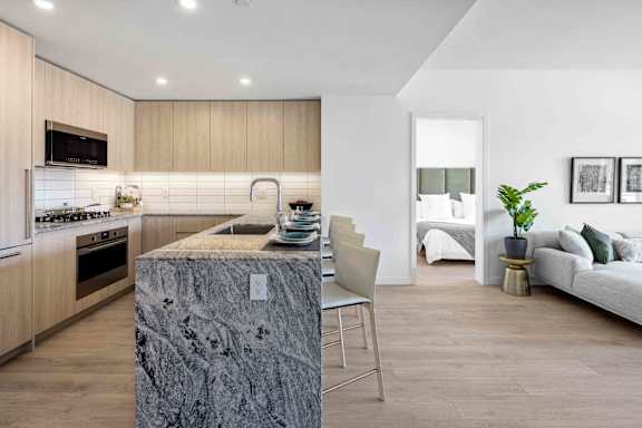 A modern kitchen with a marble island and a dining area with a white sofa.