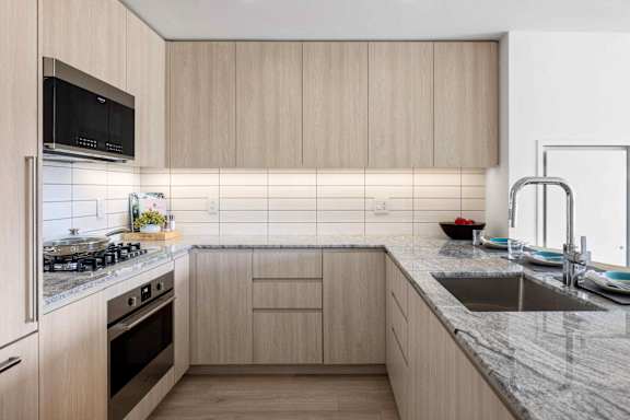A modern kitchen with wooden cabinets and a marble countertop.