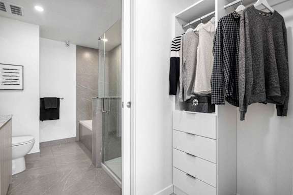 A white bathroom with a walk in shower and a towel hanging on the wall.