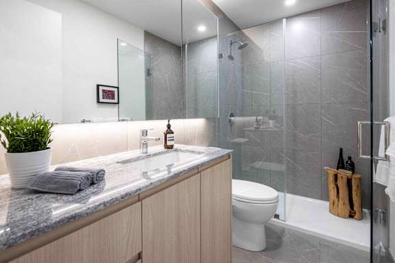 A modern bathroom with a marble countertop and a white toilet.