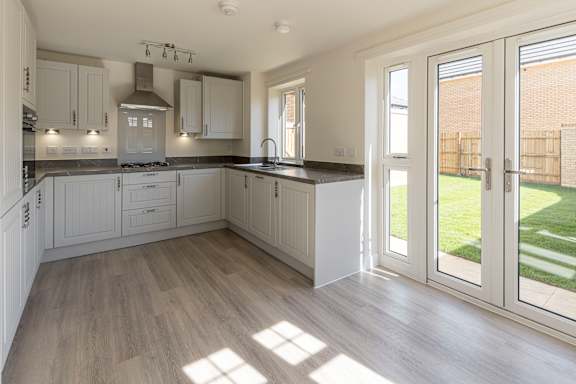 A kitchen with white cabinets and a wooden floor.
